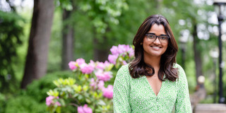 The picture shows a women (Akanksha Gavade) in front of trees. 